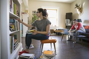 女人通过在书柜的书籍整理