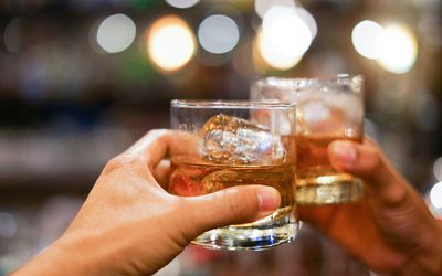 两名男子叮当响威士忌酒喝酒的酒精饮料在酒吧柜台