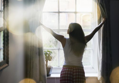 Woman opening curtains