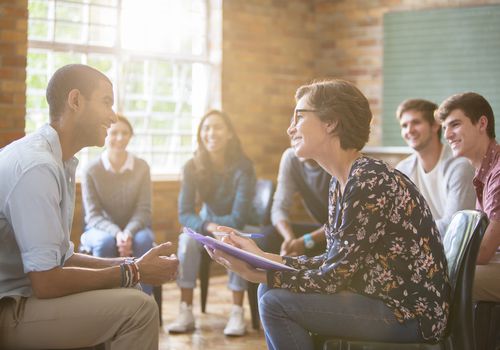 Therapist talking to client in a group setting.