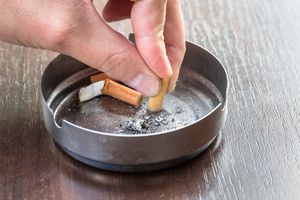 把香烟放在烟灰缸里的人