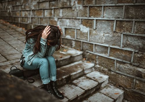 女人在楼梯上，双手抱头。