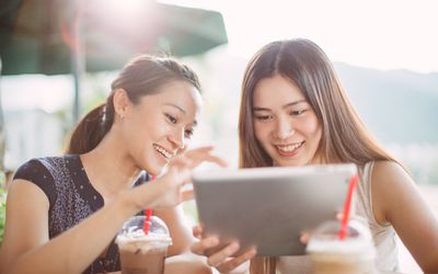 喝冷冻咖啡饮料和看片剂的两名妇女