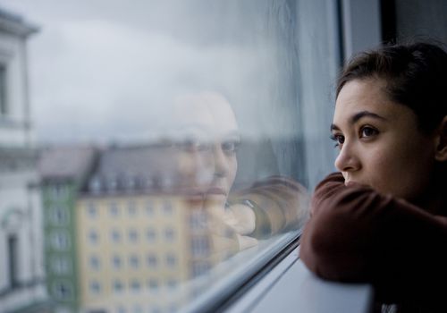 Teenager looking out of window, Munich, Germany