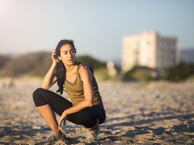 疲惫的年轻女运动员蜷缩在海滩上