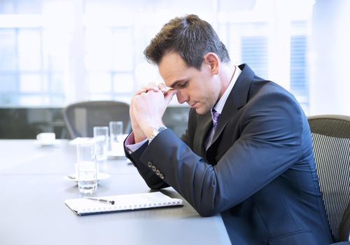 Businessman with head in hands in conference room