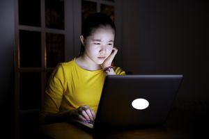 女人看着电脑屏幕在夜间