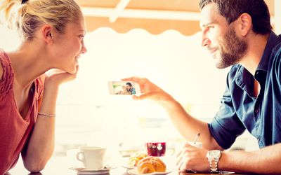 观看照片的年轻夫妇在意大利咖啡馆