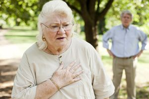 有呼吸短促和胸口痛苦的资深妇女，在背景中的老人