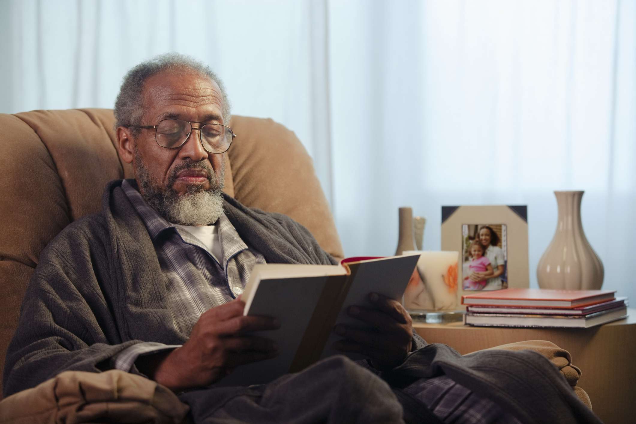 老人坐在躺椅读一本书