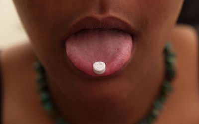 2004年，英国，一个舌头上叼着摇头丸的女孩，脸上挂着笑脸