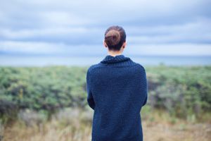 Woman in blue cardigan looking out on cloudy horizon