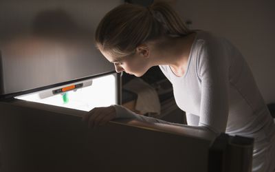 在晚上打开冰箱的妇女