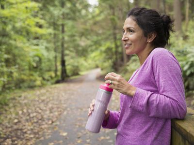 采取休息饮用水森林的微笑的妇女