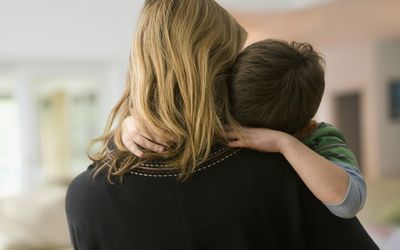 拿着她的哭泣的儿子的母亲的后面