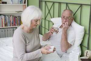 年老的妇女在床上照顾生病的丈夫