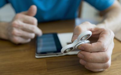 一名男子在使用智能手机时手持烦躁的旋转器