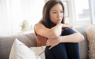 Sad mixed race woman sitting on sofa