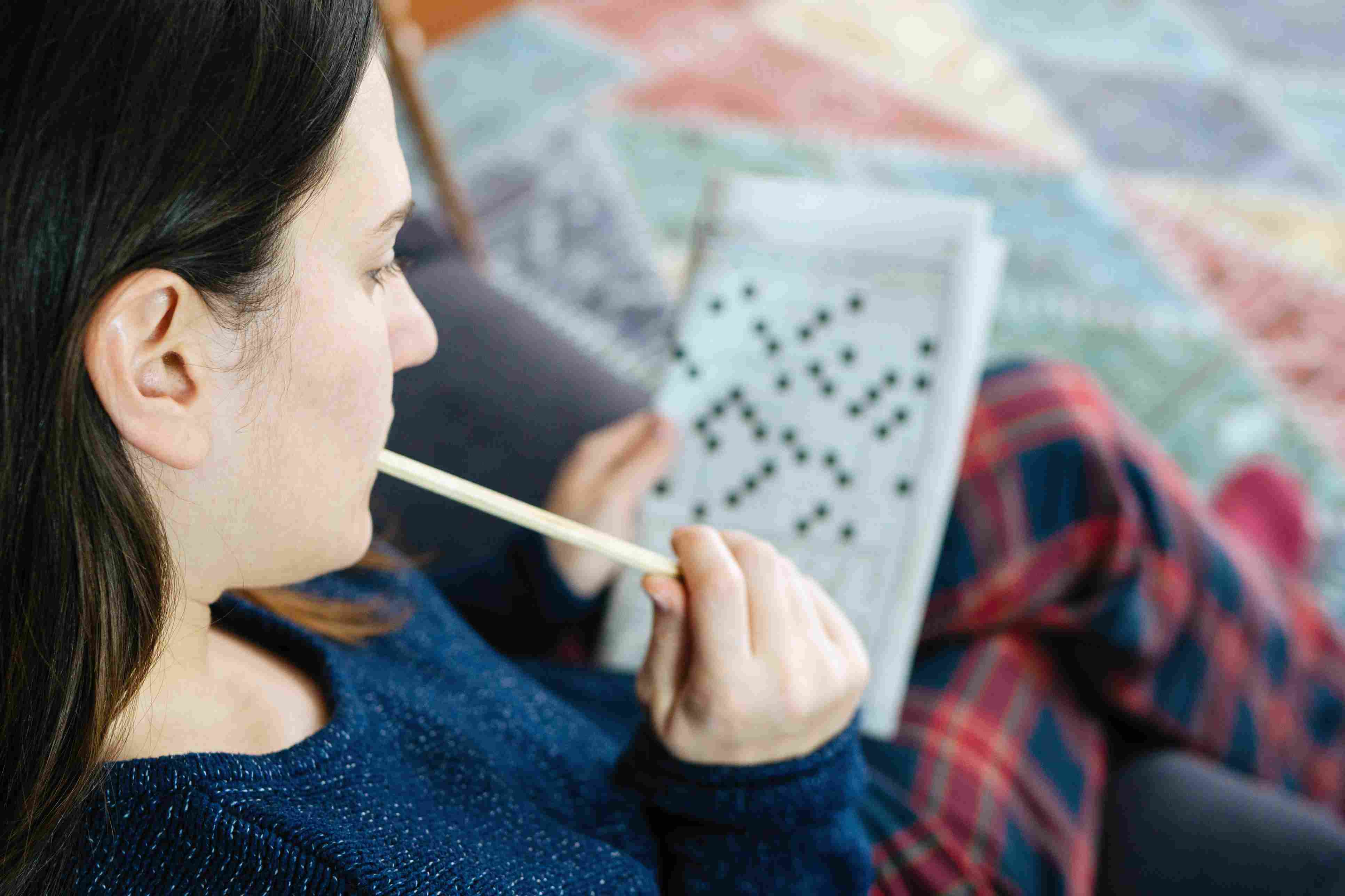 拿着铅笔的女性手和解决纵横填字谜难题