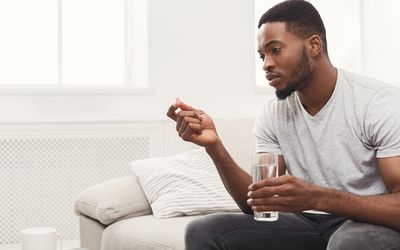 准备好的严肃的人采取药片坐长沙发