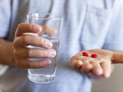 Boy holding glass of water and tablets