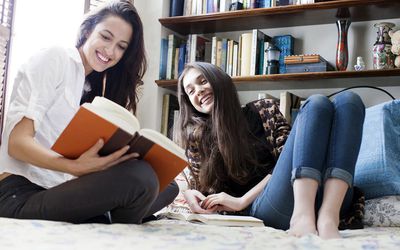 两个女朋友在床上读书和笑