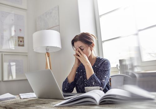 疲倦，膝上型计算机的强调的女实业家有头的头在手上