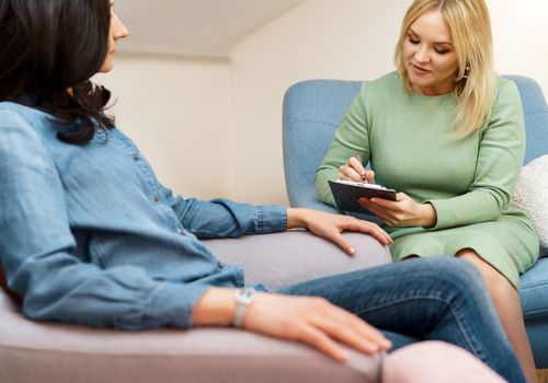 Positive blonde middle-aged woman psychologist talking to patient.