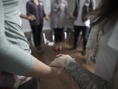 circle of people holding hands, their faces can't be seen