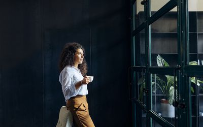 看在窗口外面的年轻女实业家在顶楼办公室“class=