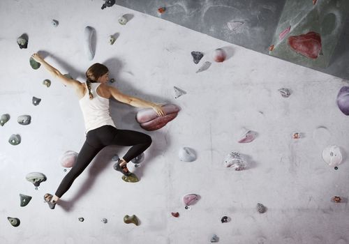 女登山者扩展攀登墙壁