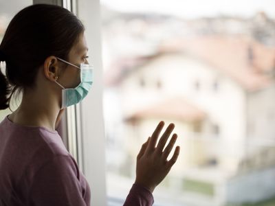Woman wearing a face mask looking out window