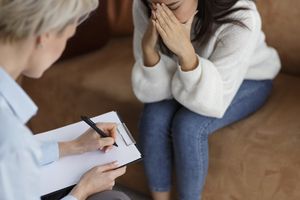 注意笔记与哭泣的妇女的心理学家在办公室，播种