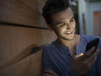 man smiling while looking at cell phone