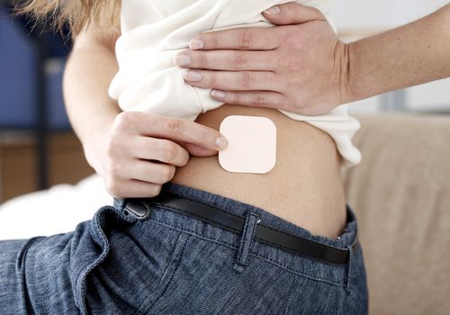 woman putting on a transdermal patch