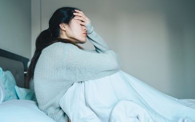 Woman in bed with head in hand.
