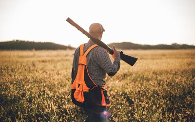 一个扛着猎枪穿过田野的人