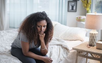 悲伤的黑人妇女坐在床上