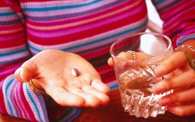 拿着药片和水的妇女