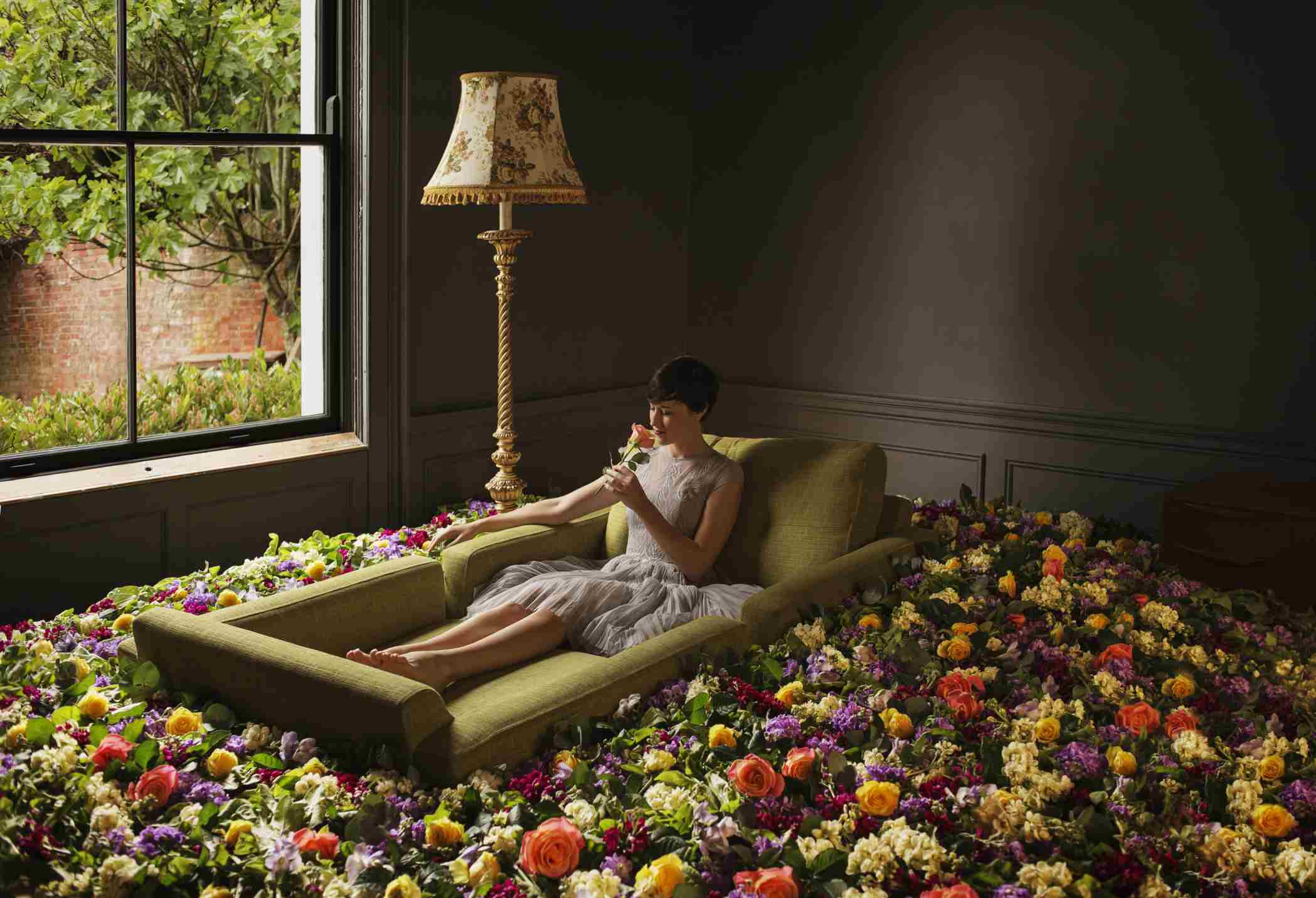 女人坐在摆满玫瑰花的房间的沙发上