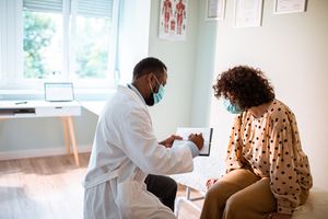 A doctor shows a patient notes in an examination room.