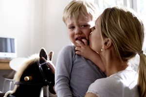 蹒跚学步的孩子在母亲的怀里哭泣