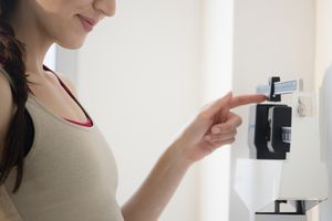 young woman weighing herself on stand-up scale
