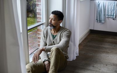 男人坐在地板上望着窗外