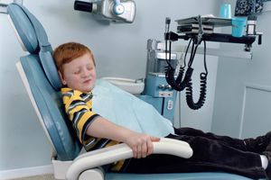 在牙医诊所里，一个惊恐的孩子紧抓着椅子的扶手