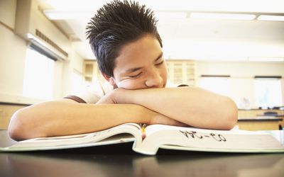 年轻男孩睡着在教科书