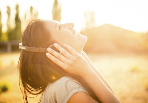 woman happily listening to music in sunshine