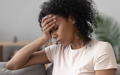 压力下躺在沙发上手放在头上的Bipoc女性