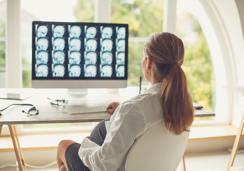 Pregnant female doctor examining brain scan