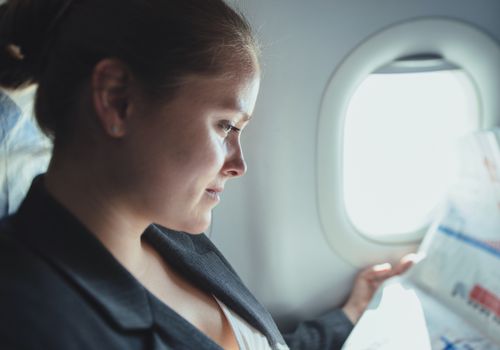 Business woman reading news in plane.